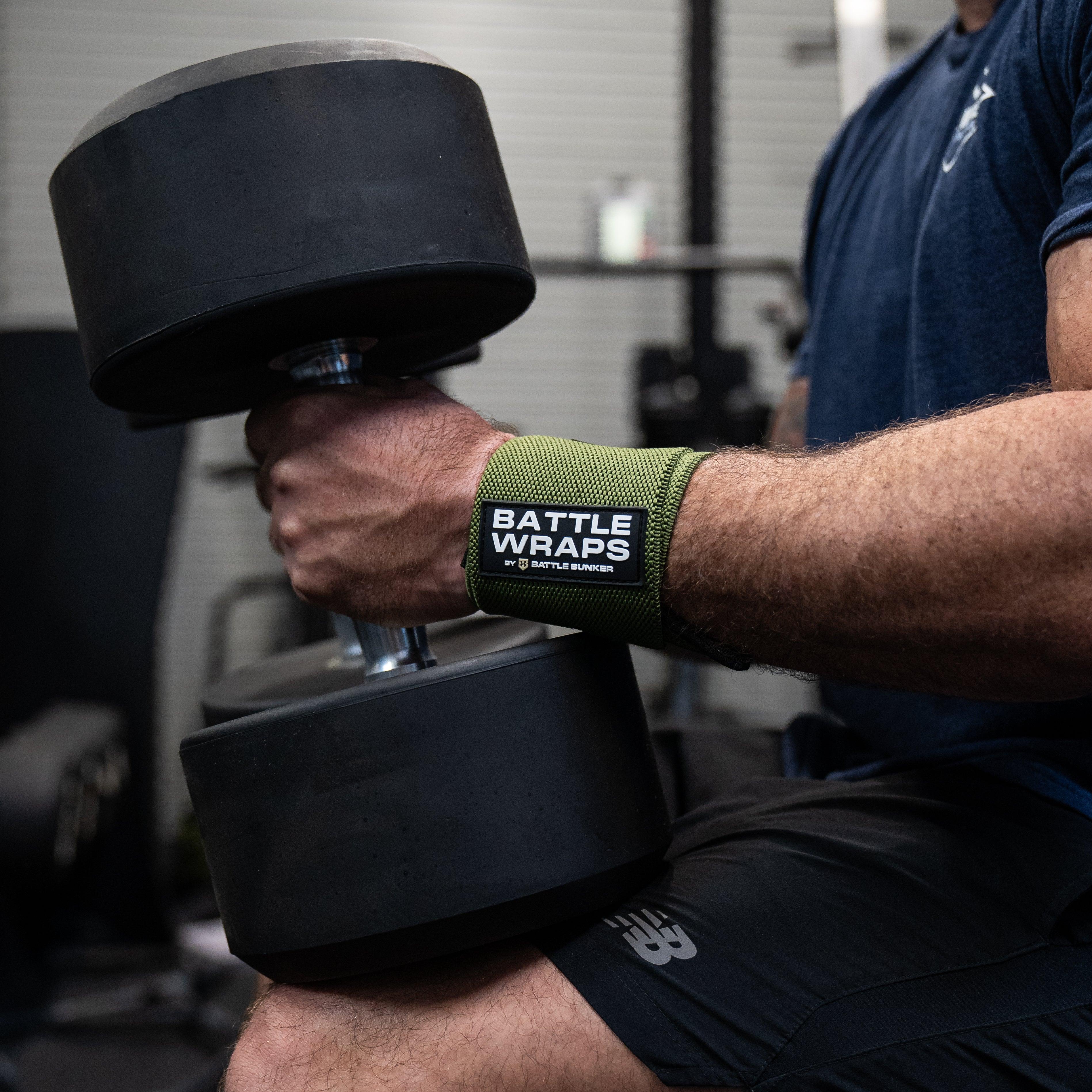 Man wearing Battle Bunker wrist wraps lifting large black dumbbell in gym setting