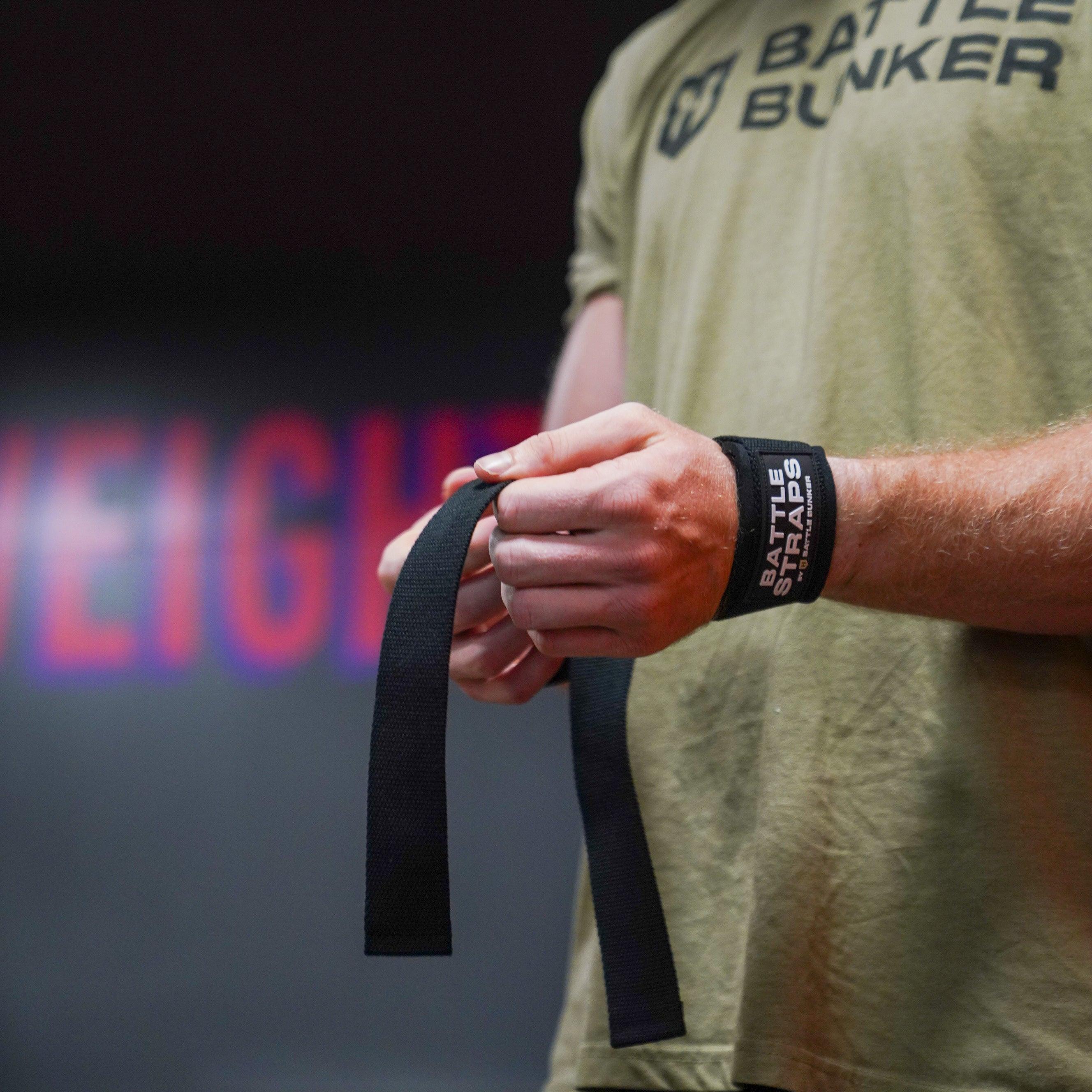 Close-up of man wearing Battle Bunker shirt and wrapping wrist with black Battle Straps wrist wraps