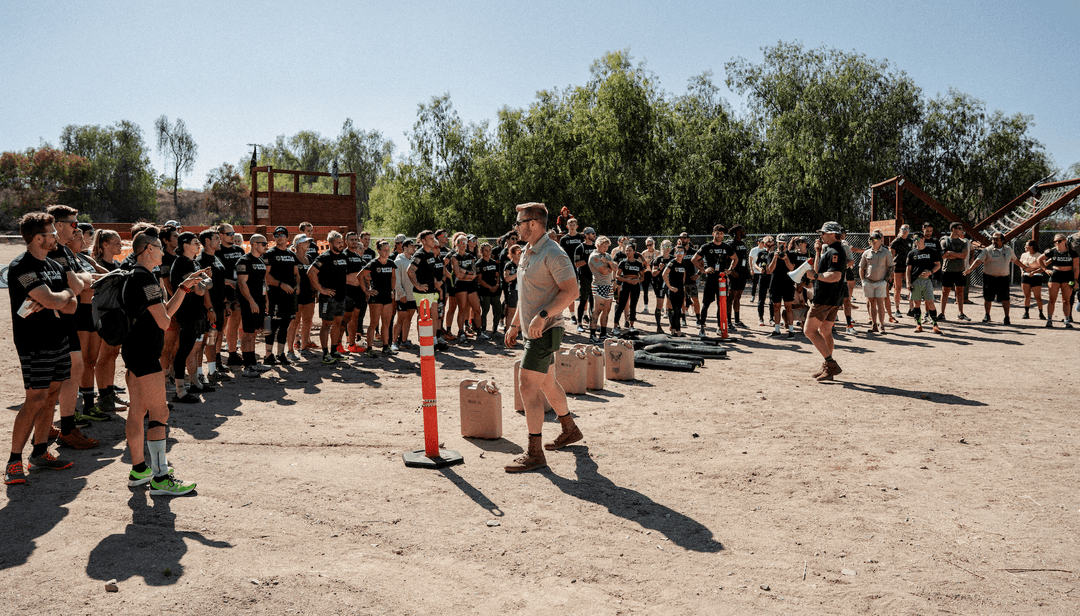 Large group of people in black Battle Bunker shirts gathered outdoors with instructors on a sunny day