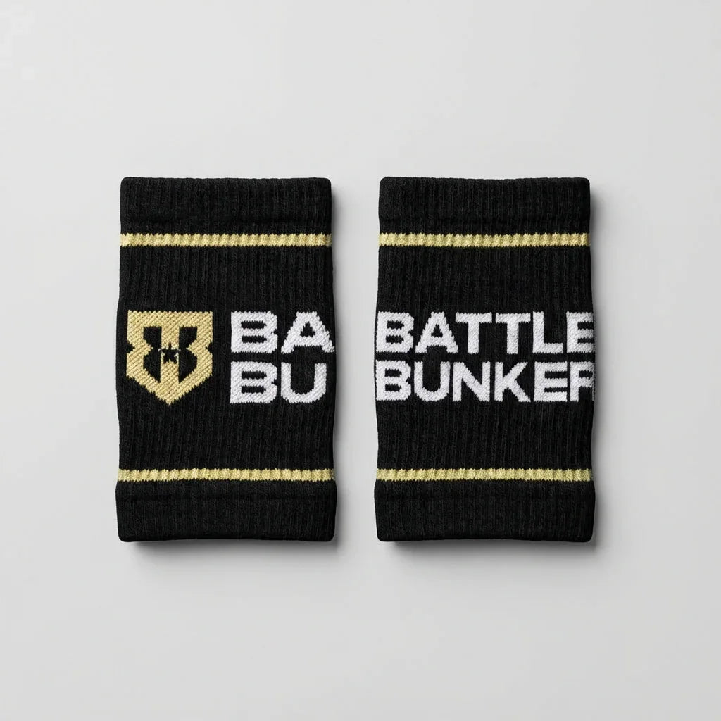 Black Battle Bunker sweat wristbands with gold stripes and white logo text on gray background