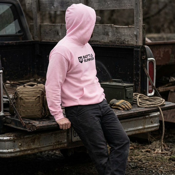 Person wearing a pink hoodie with 'Battle Bunker' logo sitting on a truck bed.