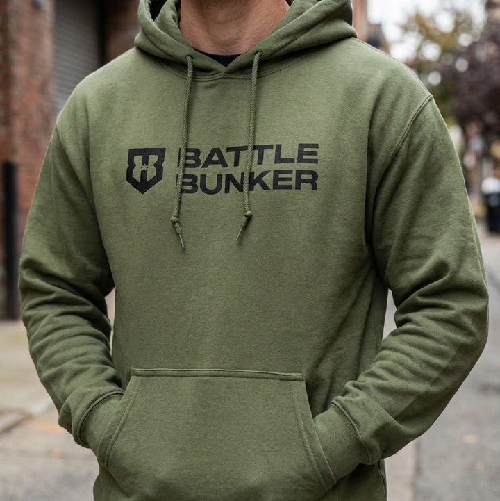 Person wearing a green hoodie with 'Battle Bunker' logo on a street.